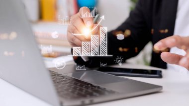 İş adamı artan bir eğilim oku ve plandan hedefe yükselen bir tablo çiziyor. Kurumsal yatırım geliştirme fikrinin bir temsili..