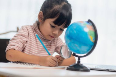 Asyalı küçük kız dünyayı kurtarma konseptini öğreniyor ve evde çocuk eğitimi için oyun aktivitesi yaparak öğreniyor..