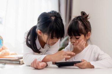 Çocukları ve aletleri kavrayın. İki küçük kız kardeş telefona bakar ve gülümser. Akıllı telefon videoları var, öğreniyorlar, oyunlar oynuyorlar, internette konuşuyorlar. Çocuklar için internet. Ebeveyn kontrolü