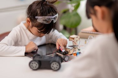 Asyalı öğrenciler evlerinde robot arabaları ve elektronik tahta kablolarını STEM, STEAM, matematik mühendisliği, bilim teknolojisi bilgisayar kodlarını çocuk konsepti için robotikte kodlayarak öğreniyorlar..