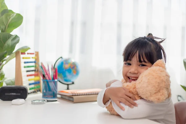 Child playing with teddy bear. Asian little girl hugging his favorite toy. Kid and stuffed animal at home.