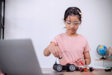 Asian students learn at home by coding robot cars and electronic board cables in STEM, STEAM, mathematics engineering science technology computer code in robotics for kids' concepts.