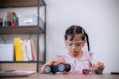 Asian students learn at home by coding robot cars and electronic board cables in STEM, STEAM, mathematics engineering science technology computer code in robotics for kids' concepts.