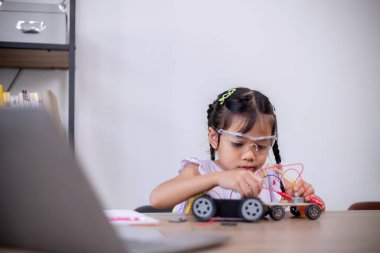 Asian students learn at home by coding robot cars and electronic board cables in STEM, STEAM, mathematics engineering science technology computer code in robotics for kids' concepts.