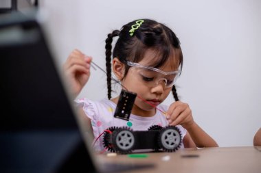 Asian students learn at home by coding robot cars and electronic board cables in STEM, STEAM, mathematics engineering science technology computer code in robotics for kids' concepts.