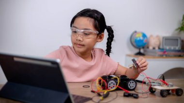 Asian students learn at home by coding robot cars and electronic board cables in STEM, STEAM, mathematics engineering science technology computer code in robotics for kids' concepts.