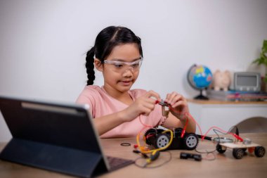 Asian students learn at home by coding robot cars and electronic board cables in STEM, STEAM, mathematics engineering science technology computer code in robotics for kids' concepts.