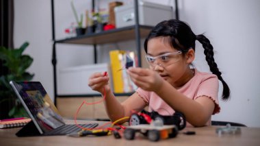 Asian students learn at home by coding robot cars and electronic board cables in STEM, STEAM, mathematics engineering science technology computer code in robotics for kids' concepts.