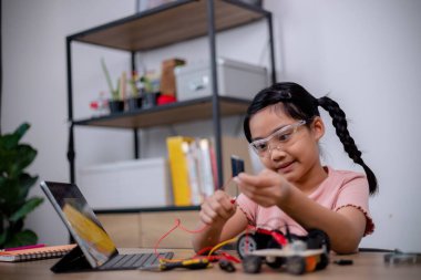 Asian students learn at home by coding robot cars and electronic board cables in STEM, STEAM, mathematics engineering science technology computer code in robotics for kids' concepts.