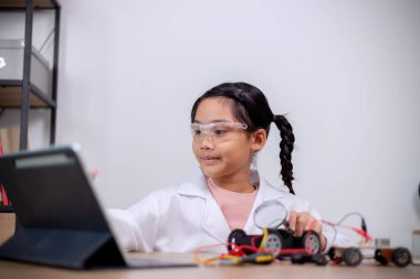 Asian students learn at home by coding robot cars and electronic board cables in STEM, STEAM, mathematics engineering science technology computer code in robotics for kids' concepts.