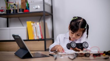 Asian students learn at home by coding robot cars and electronic board cables in STEM, STEAM, mathematics engineering science technology computer code in robotics for kids' concepts.