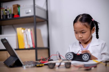 Asian students learn at home by coding robot cars and electronic board cables in STEM, STEAM, mathematics engineering science technology computer code in robotics for kids' concepts.