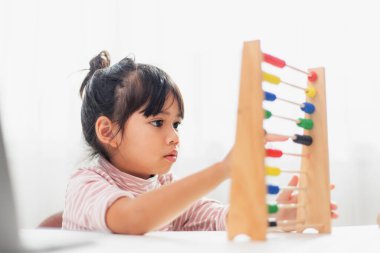 Genç ve tatlı bir Asyalı kız abaküsü renkli boncuklarla evde saymayı öğrenmek için kullanıyor.