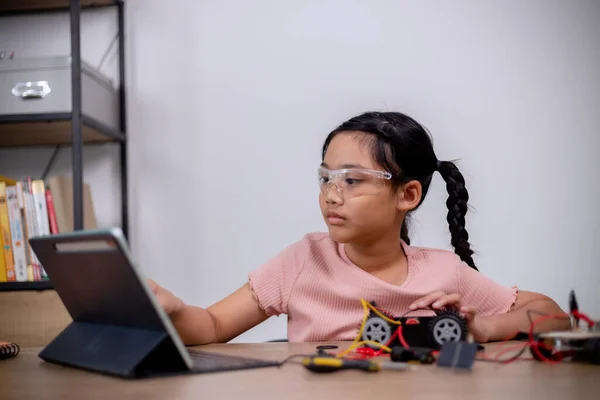 Asian students learn at home by coding robot cars and electronic board cables in STEM, STEAM, mathematics engineering science technology computer code in robotics for kids\' concepts.