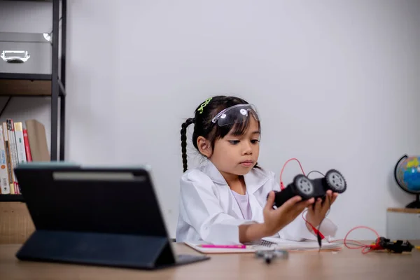 Asian students learn at home by coding robot cars and electronic board cables in STEM, STEAM, mathematics engineering science technology computer code in robotics for kids\' concepts.