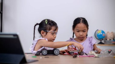 Asian students learn at home by coding robot cars and electronic board cables in STEM, STEAM, mathematics engineering science technology computer code in robotics for kids' concepts.