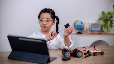 Asian students learn at home by coding robot cars and electronic board cables in STEM, STEAM, mathematics engineering science technology computer code in robotics for kids' concepts.