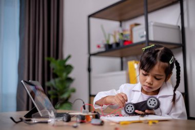 Asian students learn at home by coding robot cars and electronic board cables in STEM, STEAM, mathematics engineering science technology computer code in robotics for kids' concepts.