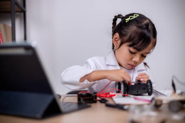 Asian students learn at home by coding robot cars and electronic board cables in STEM, STEAM, mathematics engineering science technology computer code in robotics for kids' concepts.