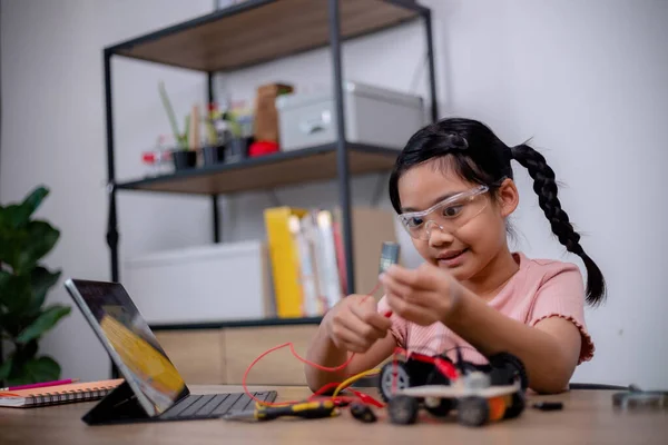 Asian students learn at home by coding robot cars and electronic board cables in STEM, STEAM, mathematics engineering science technology computer code in robotics for kids' concepts.