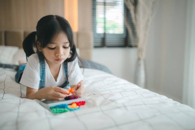 Asyalı çocuk yatak odasında oyuncaklarla oynuyor..