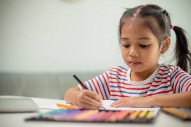 Asyalı çocuk öğrenciler yeni fikirlerin ne olduğunu öğrenmek için ödev yapıyorlar. Eğitim kavramı.