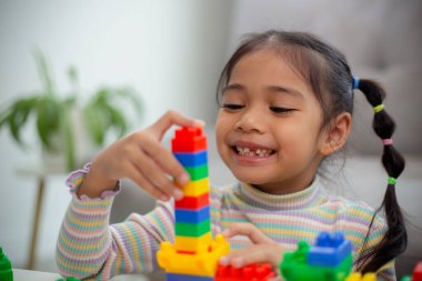 Adorable little girl playing toy blocks in a bright room	 clipart