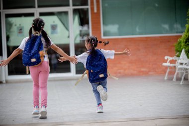 Okula dönelim. Sırt çantalı şirin Asyalı kız çocuğu koşuyor ve okula eğlenerek gidiyor.