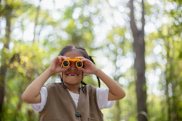 stock image Happy Little Asian girls looking ahead and smiling child with the binoculars in the park. Travel and adventure concept. Freedom, vacation