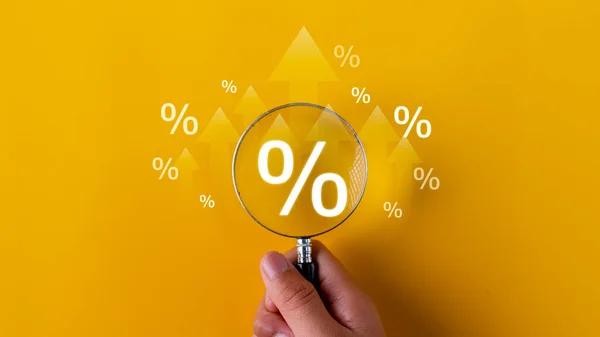 Interest rate and dividend concept. magnifying glasses and percentage symbols and an up arrow, interest rates continue to increase, and return on stocks and mutual funds. on yellow background