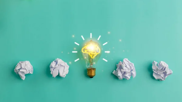 Idea concept with crumpled paper and a light bulb on a blue background. Creative thinking ideas and innovation concepts.