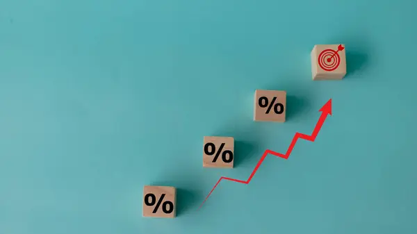 Concept of increasing sales. Wooden cubes with percentage icon and Rising arrow red on blue background. investment growth goals concept.