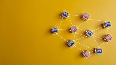Sarı zemin üzerinde birbirine bağlı bilgisayar ve dizüstü simgeli tahta küpleri. Bilgisayar ağı veya iletişim kavramı. 