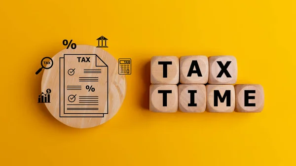 Tax time concept with text on wooden cubes on a yellow background. Tax payment reminder or annual taxation concept.