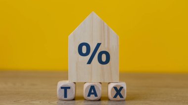 Property tax concept. investment planning.Wooden blocks with the word TAXES and a house on a yellow background. clipart