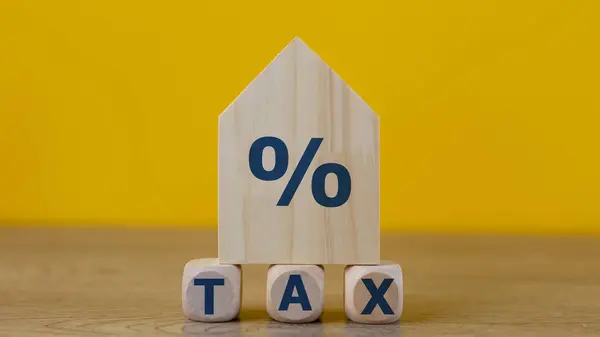 Property tax concept. investment planning.Wooden blocks with the word TAXES and a house on a yellow background.