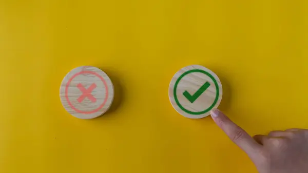 Right and wrong or voting yes or no concept. Wooden blocks with check marks on a yellow background. The idea of choice.