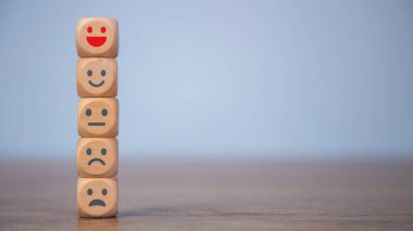 Müşteri değerlendirmesi olumlu ya da olumsuz değerlendirme, insan sağlığı ve sağlık kontrolü. Dünya Akıl Sağlığı Günü, Pozitif ve Memnuniyet Düşünme Anketi konsepti. Duygu simgeleriyle dolu tahta küpler.