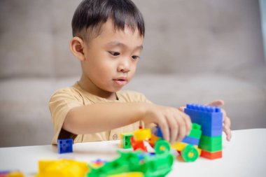 Renkli oyuncak bloklarıyla oynayan çocuk. Küçük çocuk oyuncaklardan araba yapıyor. Küçük çocuklar için eğitici ve yaratıcı oyuncaklar ve oyunlar. 