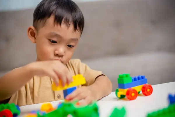 The kid playing with colorful toy blocks. Little boy building the car of block toys. Educational and creative toys and games for young children.