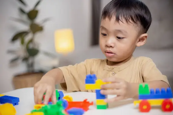 The kid playing with colorful toy blocks. Little boy building the car of block toys. Educational and creative toys and games for young children.