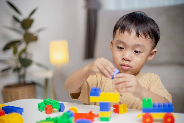 Ребенок играет с красочными игрушечными блоками. Маленький мальчик строит машину из блочных игрушек. Образовательные и творческие игрушки и игры для маленьких детей. 