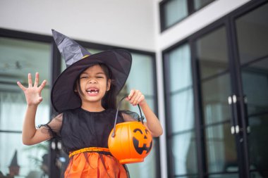 Cadılar Bayramı için cadı kostümü giymiş mutlu Asyalı kız çocuğu. Şeker mi şaka mı? Çocuklar şaka mı şeker mi?.