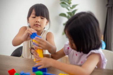 Parlak bir odada oyuncak blokları oynayan sevimli küçük kız.