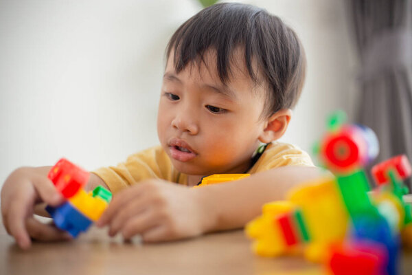 Симпатичный маленький мальчик играет с красочными игрушками 