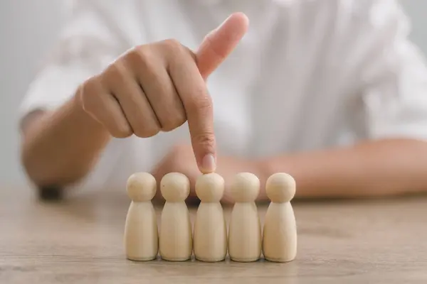 HR manager (human resources) or Employer\'s hand chooses to take person wooden doll. The leader stands out from the crowd. Looking for good worker. HR, HRM, HRD concepts.