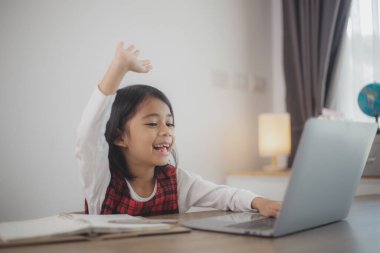 Şirin ve mutlu Asyalı kız çocukları dizüstü bilgisayar kullanıyor, evde online bir e-öğrenme sistemi üzerinden çalışıyorlar..
