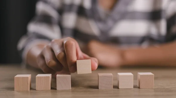 Businesswomen stack blank wooden cubes on the table with copy space, empty wooden cubes for input wording, and an infographic icon.