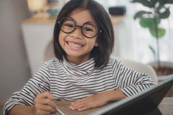 Cute Asian little girl children using a laptop computer, studying through an online e-learning system.