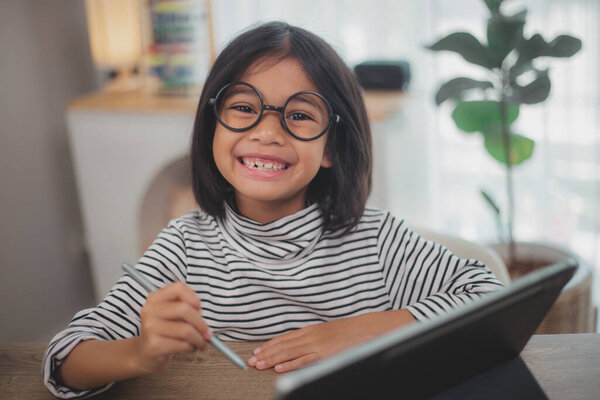 Cute Asian little girl children using a laptop computer, studying through an online e-learning system.